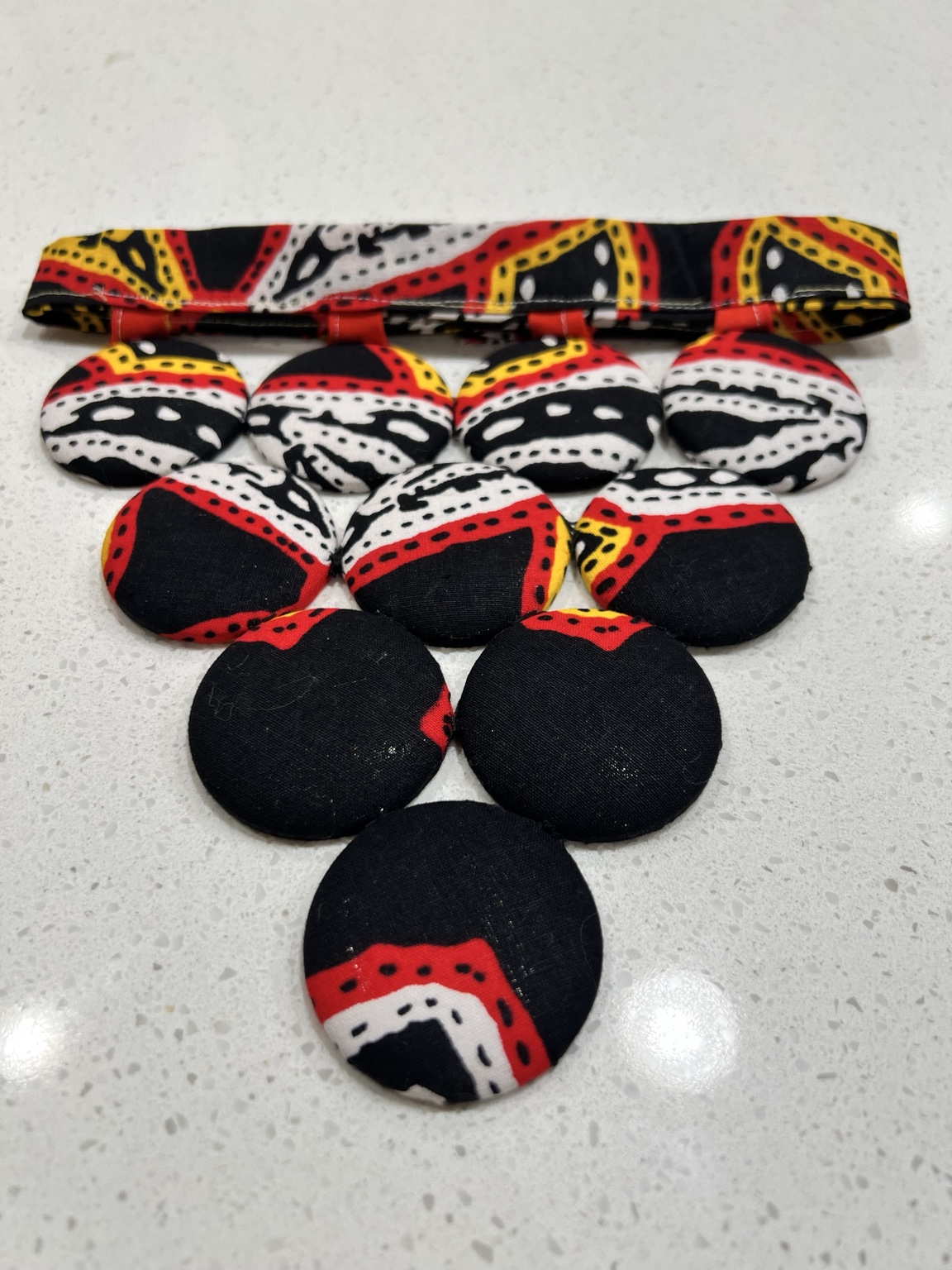 Statement necklace with red, black, yellow, and white fabric circles